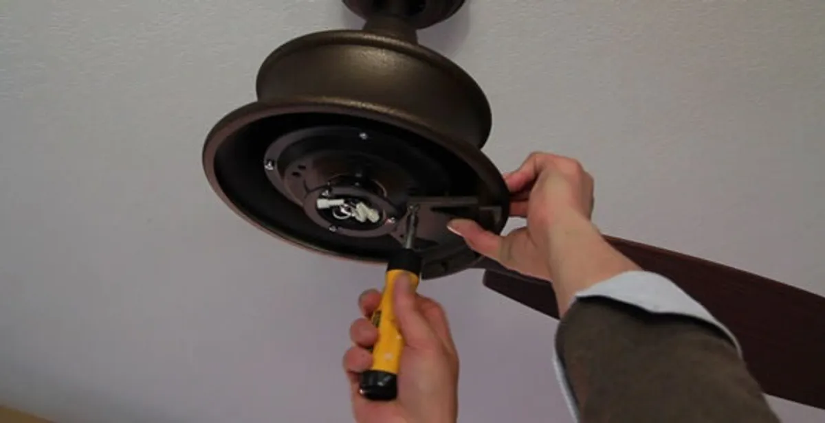 Electrician installing ceiling fan mounting bracket and fixture in Cambridge, MA